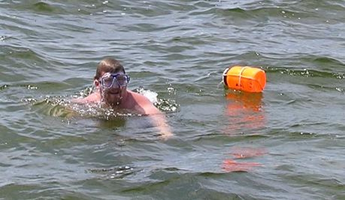 Nick swimming in a lake with an orange buoy.
